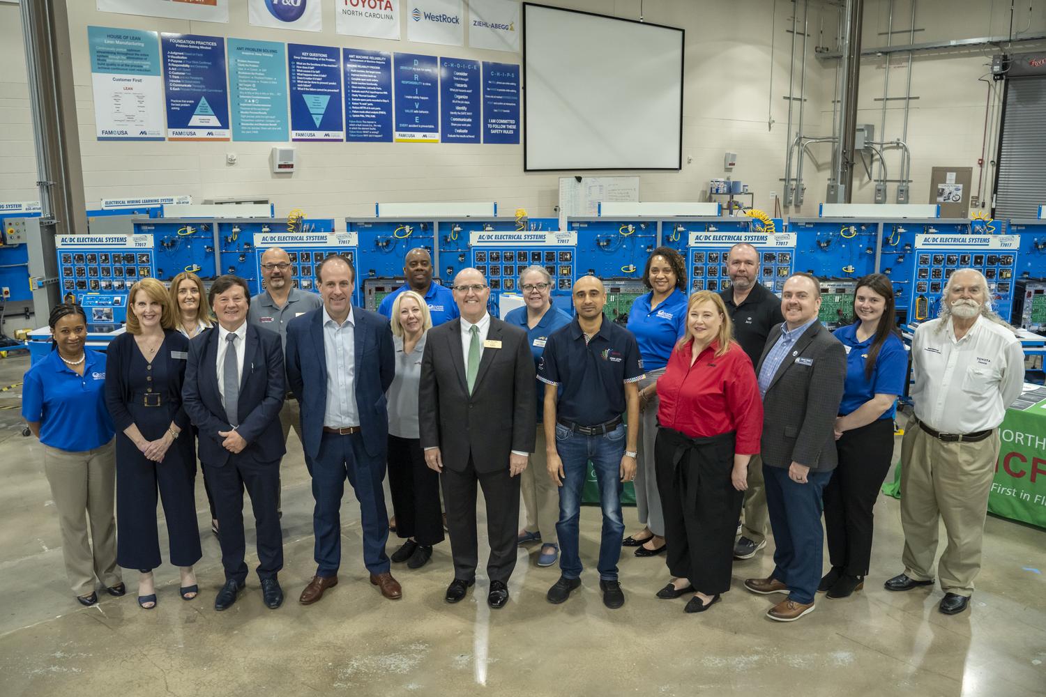 GTCC staff, visitors from Ireland and South Africa, FAME employees, and Guilford County Schools employees pose for a group photo inside GTCC's FAME space in the Center for Advanced Manufacturing.