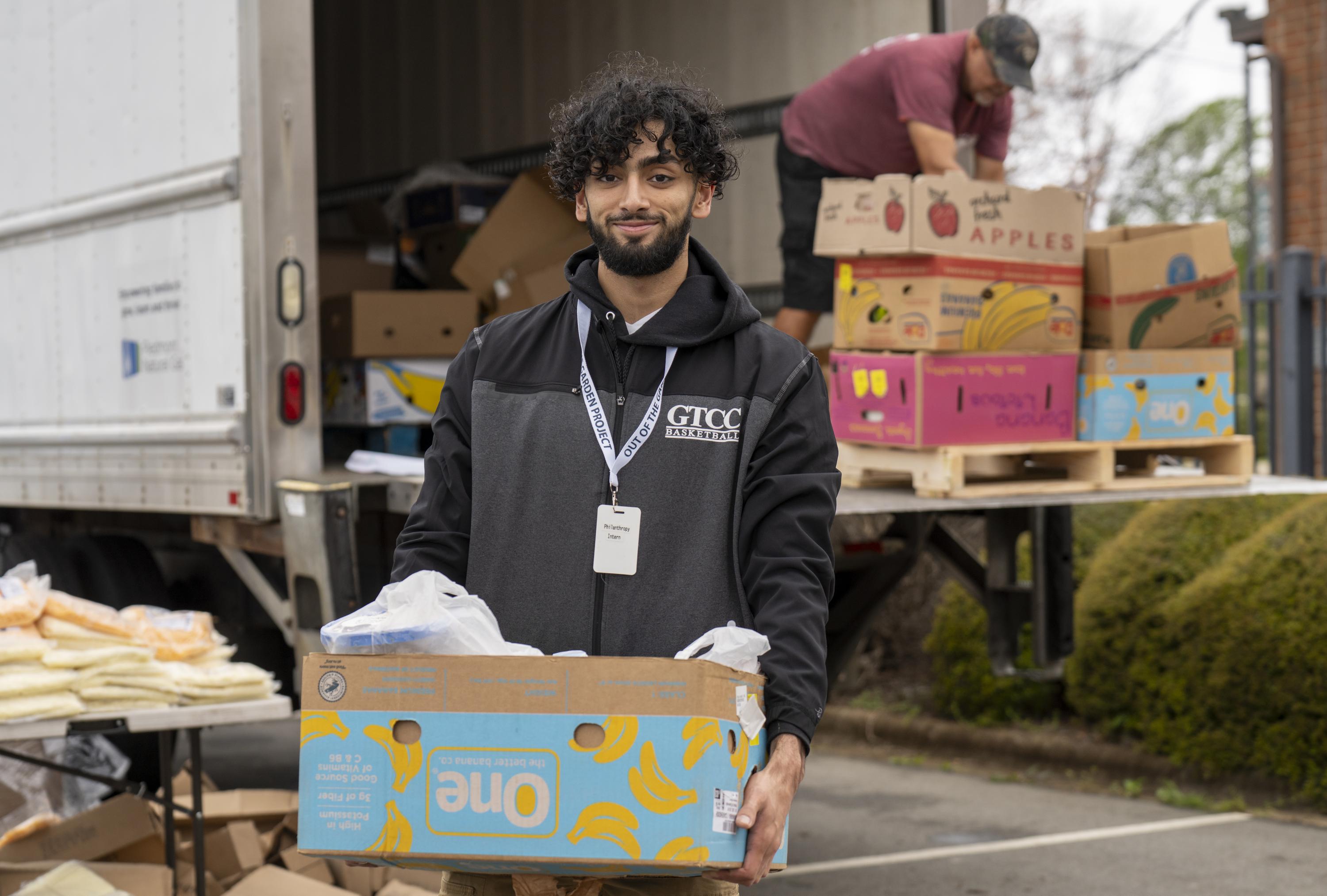 Sameer Qureshi holds a box of food at the Out of the Garden Fresh Mobile Market.