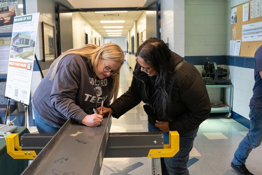 Two GTCC students signing the final GTCC Aviation Center beam