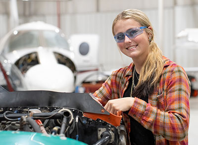 Female Aviation System Technology Student working on plane
