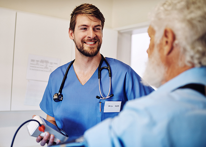 A male nursing assistant talks with a patient.