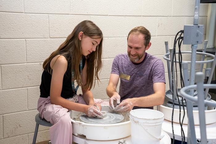 Clay creation student and instructor creating pottery on a pottery wheel