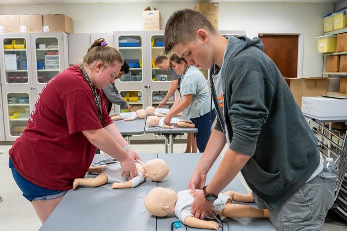 Future Educator students performing chest compressions on dummy babies
