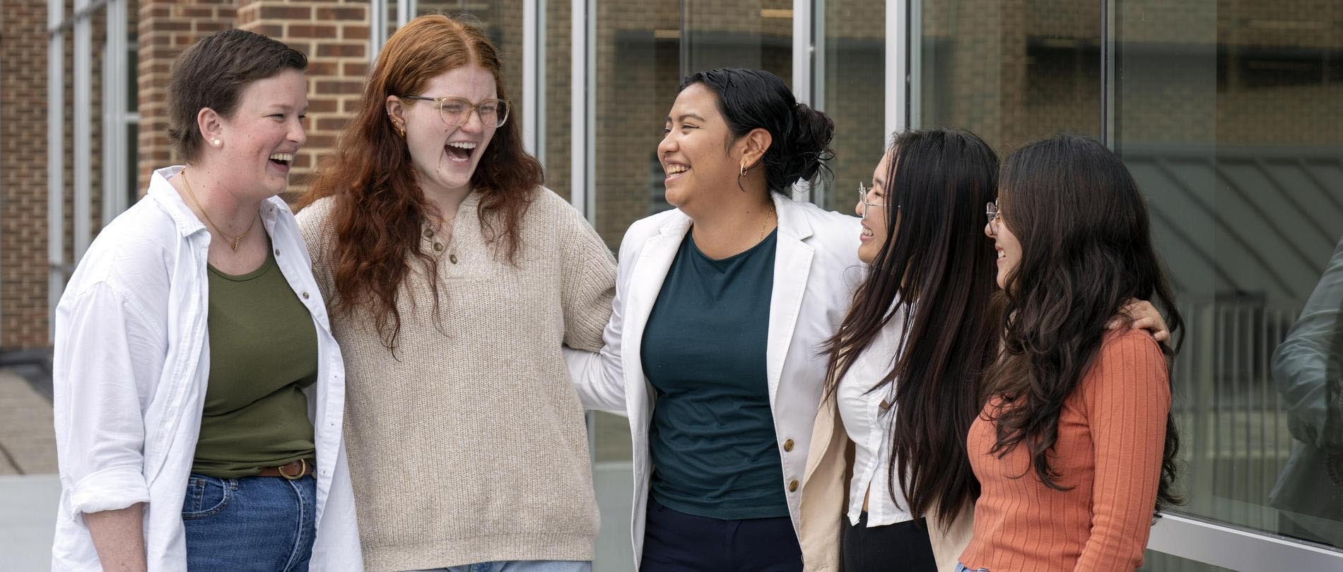 Five Honors Program students laugh together on campus