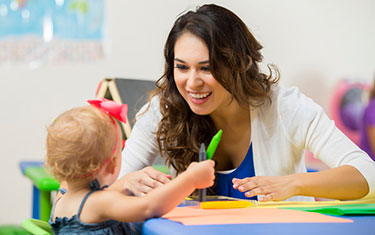 Young woman works with a child in the classroom.