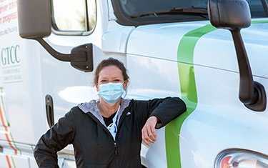Woman poses in front of a large truck during commercial drivers license class.