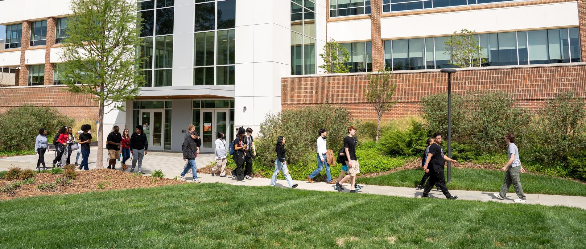 Group of students walking together on a guided campus tour outside a modern academic building at GTCC.