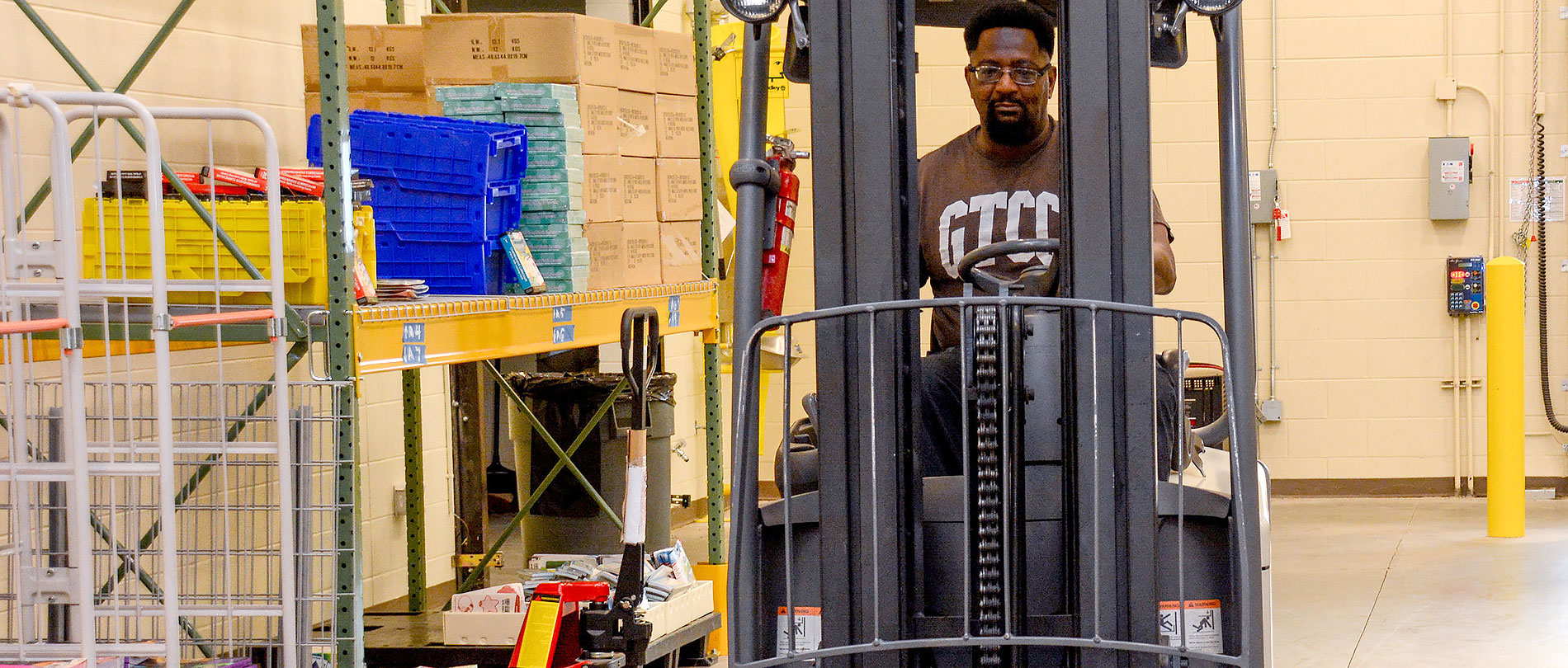 GTCC students drives forklift and moves boxes in classroom warehouse.