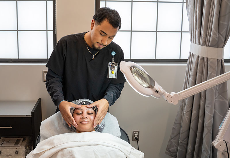 A student gives a customer a facial.