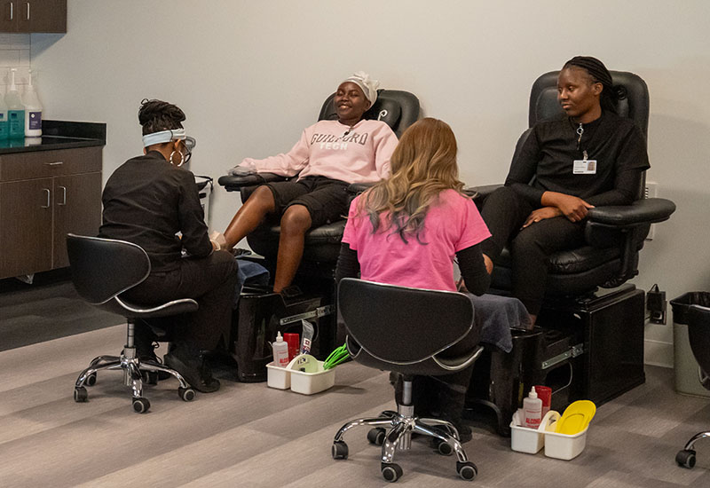 Students give pedicures to customers.