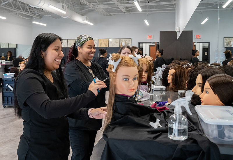 Student cut hair on mannequins.