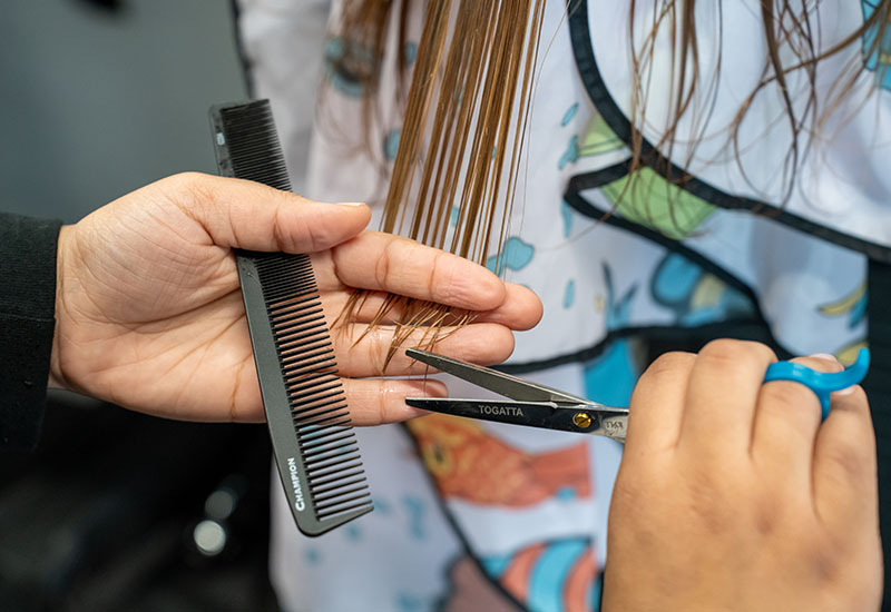 A student cuts a mannequin's hair.