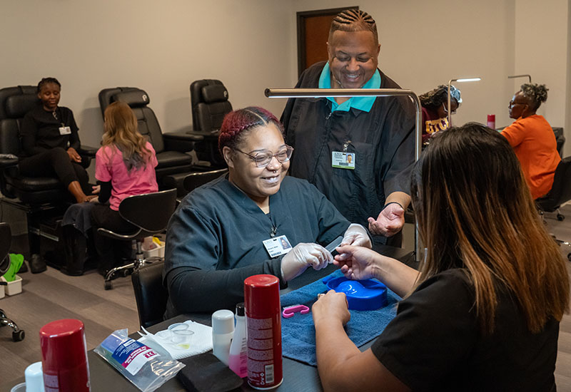 A student gives a manicure to a customer.