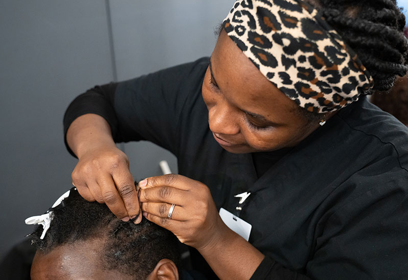 A student styles a customer's hair.