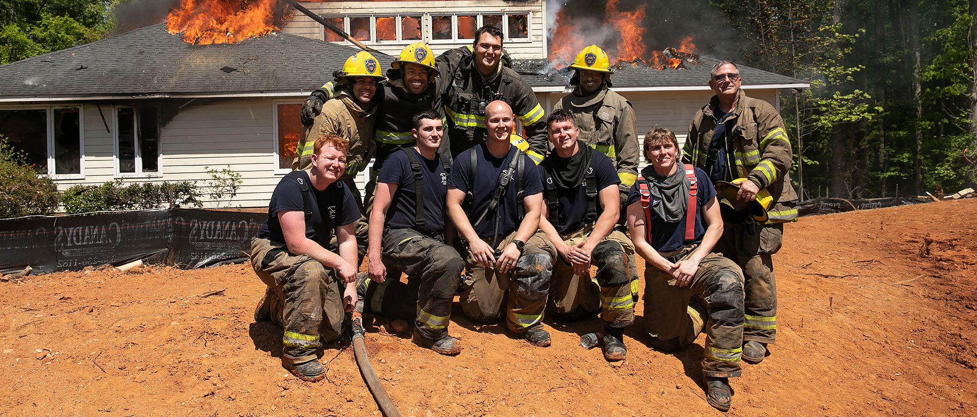 Fire cadets in the GTCC Fire Academy pose after completing their live burn assignment by letting an approved house burn down in Summerfield, North Carolina