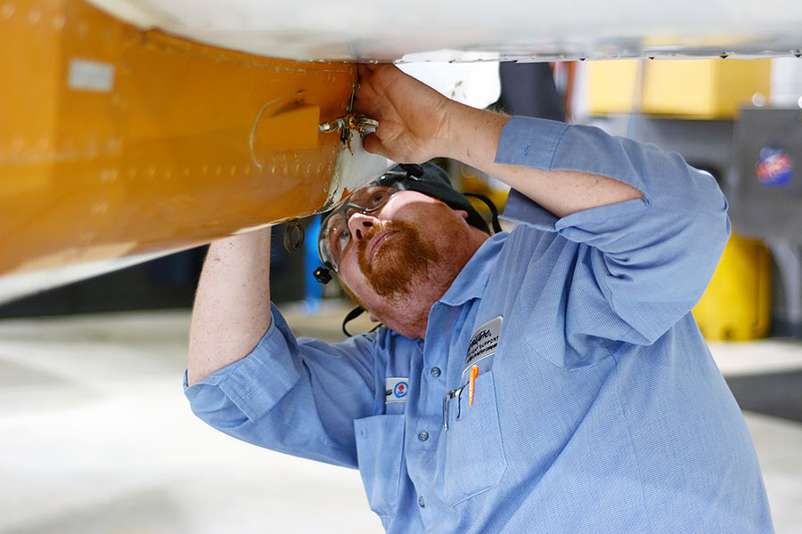 Student assembles parts on a plane fuselage.