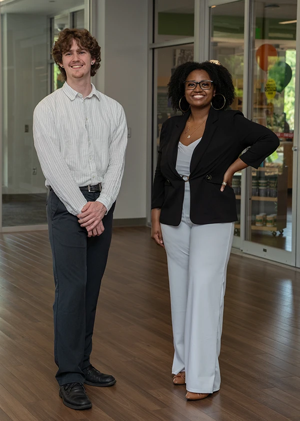 A male and a female student model basic dress for graduation in black and white clothings.