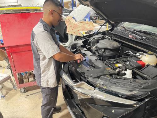 Tim Gallardo works on a car body.