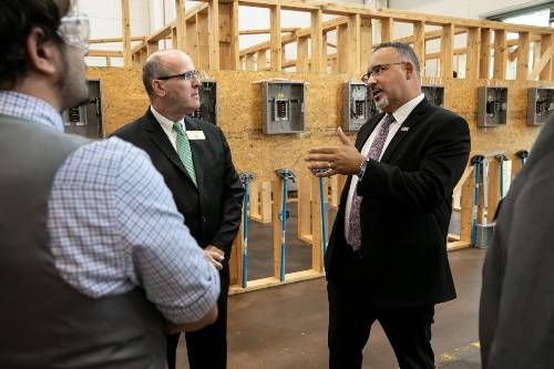 Secretary Miguel Cardona speaks with GTCC President Anthony Clarke while touring the electrical lab on the Greensboro campus.