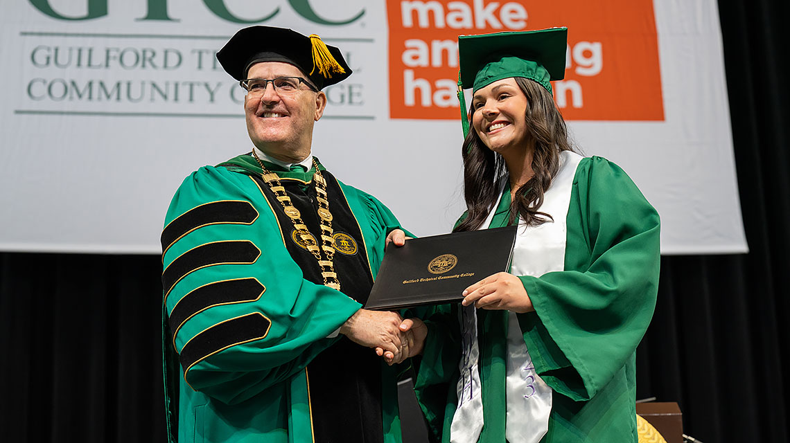 GTCC President Anthony Clarke presents a diploma to a student.