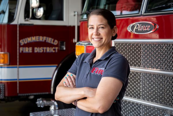 Jenna Daniels crosses her arms standing in front of a fire engine.