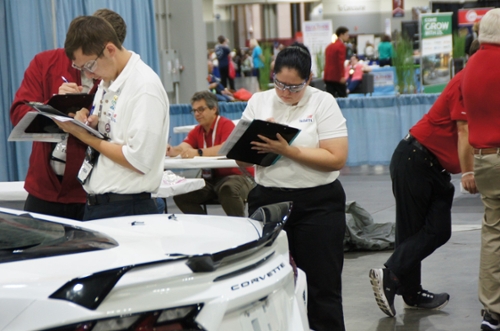Lauren Lewis (center) evaluates a car for the collision damage appraisal category.