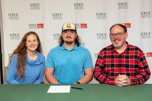 Anthony Hauser, flanked by two adults, signs his letter of intent to play baseball for The Citadel.