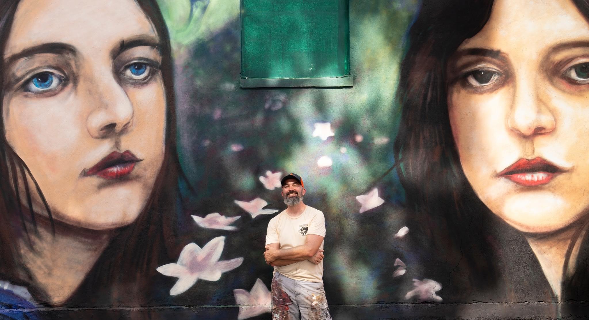 Douglas Cason poses with a photo of the mural he created in Texas.