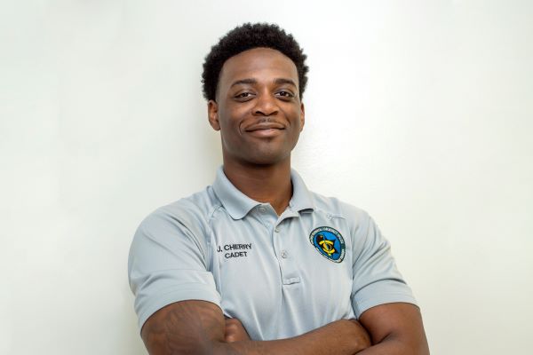 A male in a GTCC BLET polo poses for a portrait with his arms crossed.