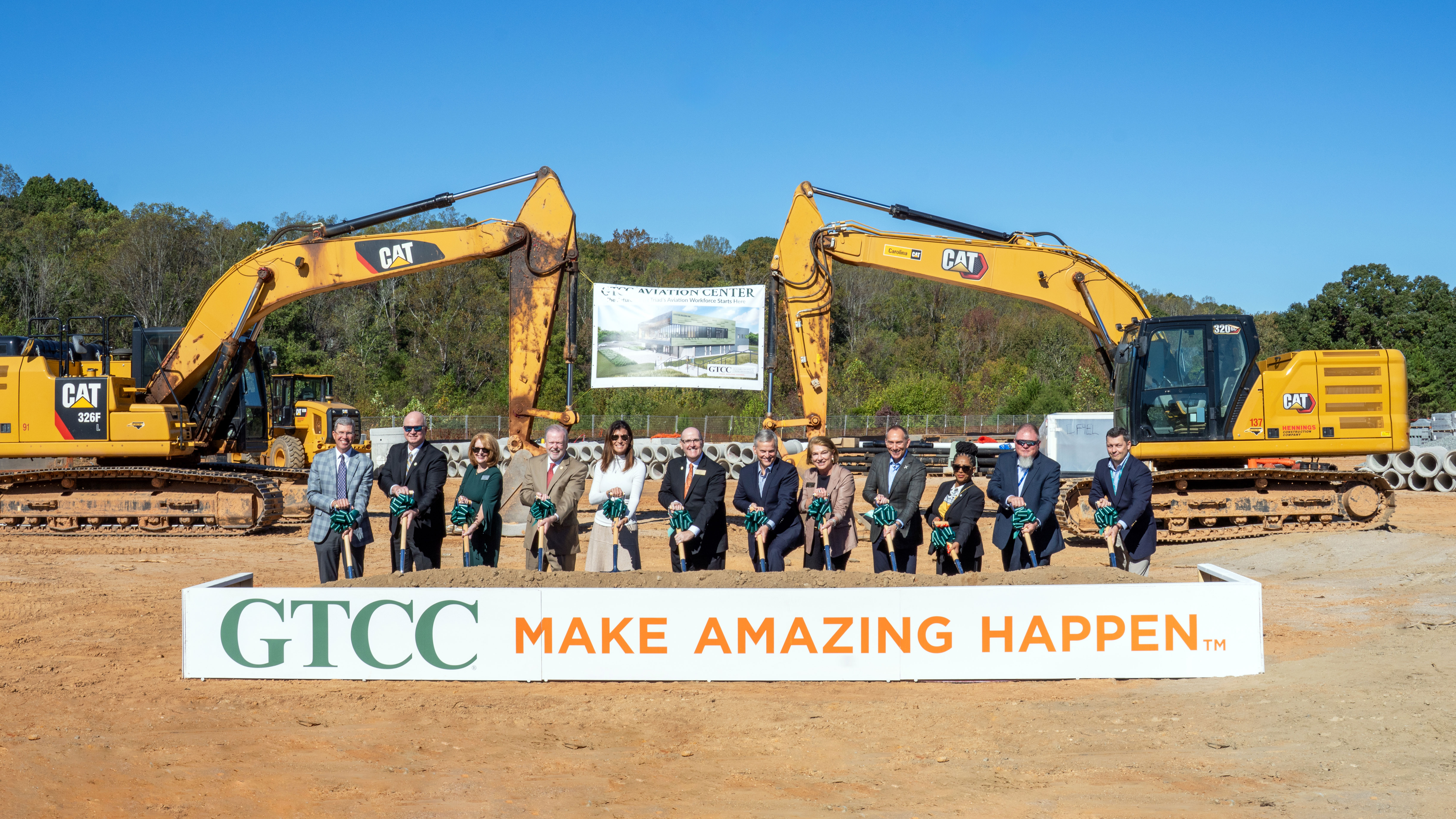 GTCC leaders and partners participate in the Aviation Center groundbreaking ceremony, standing with shovels in front of construction equipment and a banner displaying the future facility rendering.