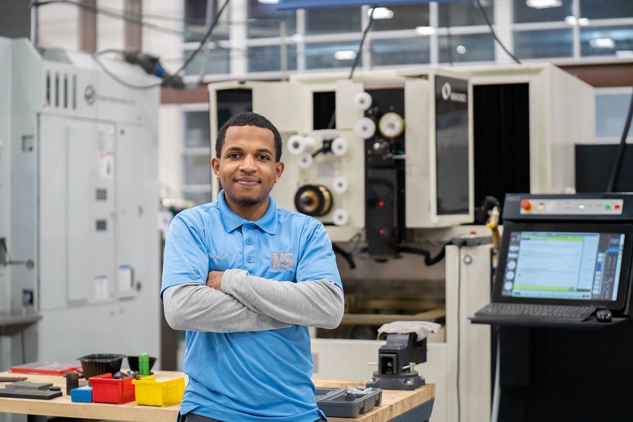 GTCC student Dylan Clark standing in a production center, looking at the camera smiling with his arms folded 