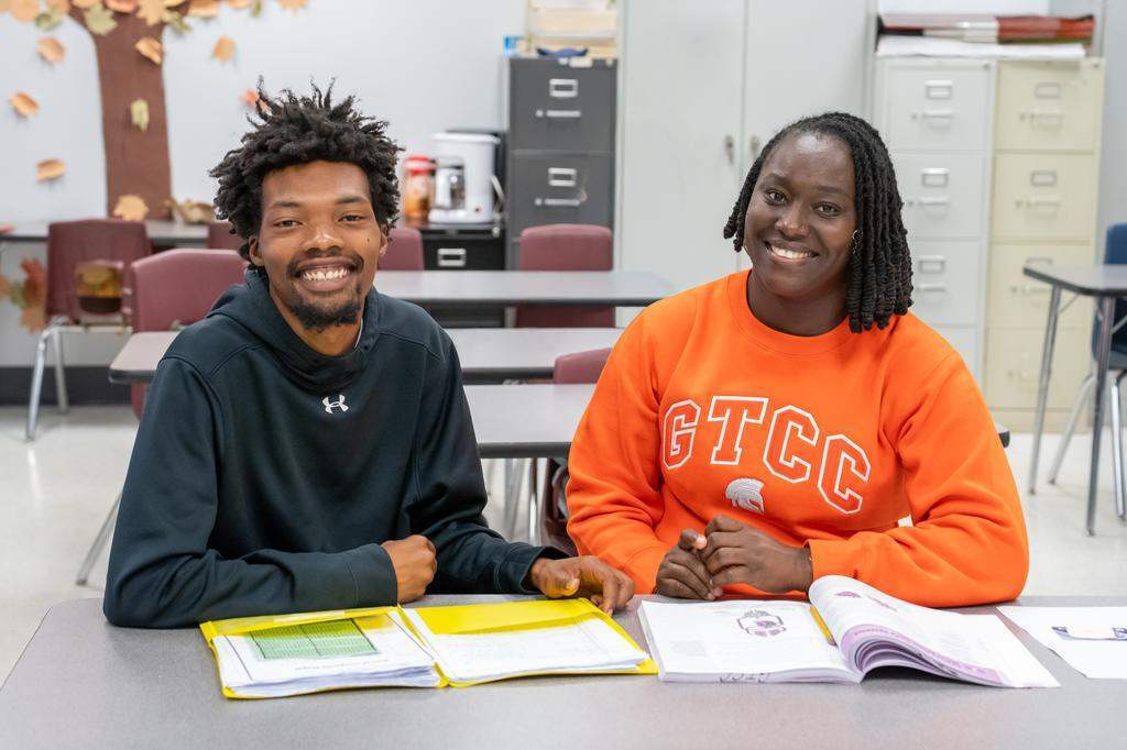 GED boot camp students Phillip Underwood and Stacia Clair smiling at the camera while seated in a classroom.